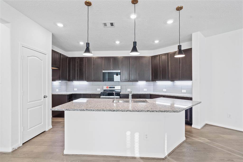 This kitchen is by far any chef’s dream! This spacious kitchen features high ceilings, wood cabinets, granite countertops, SS appliances, modern tile backsplash, recessed and pendant lighting, extended counter space, granite kitchen island with double sink and space for breakfast bar, and a walk-in pantry all overlooking your huge family room.