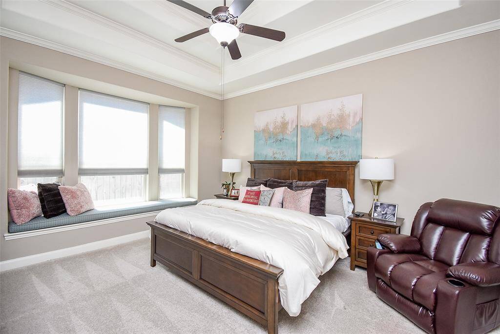 Primary bedroom with special details in its custom window seat; multi level tray ceiling; and crown molding.