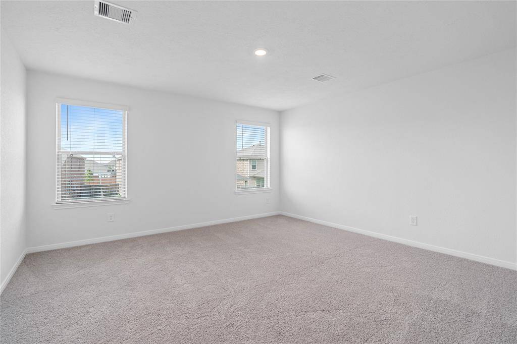 Come and unwind after a long day in this magnificent primary suite! This spacious room features plush carpet, warm paint, high ceilings, recessed lighting, and large windows with privacy blinds.
