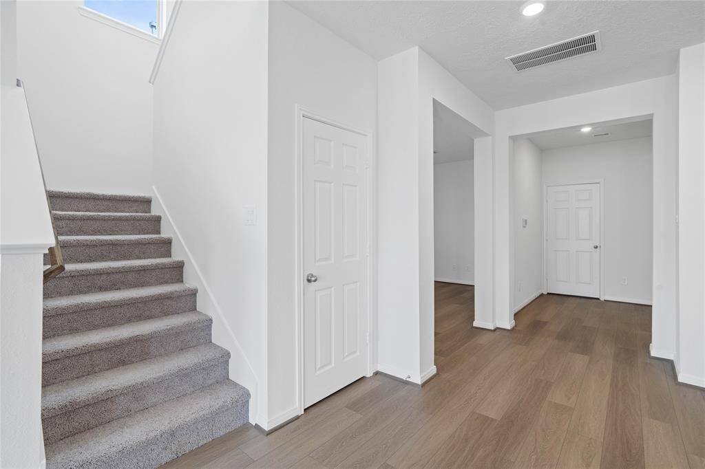 As you walk in to 21134 Montego Bay, the entryway is open and bright! Featuring gorgeous vinyl plank flooring, bright neutral paint, and recessed lighting. This view highlights the entrance to Den, under stair storage closet, and staircase leading to second floor.
