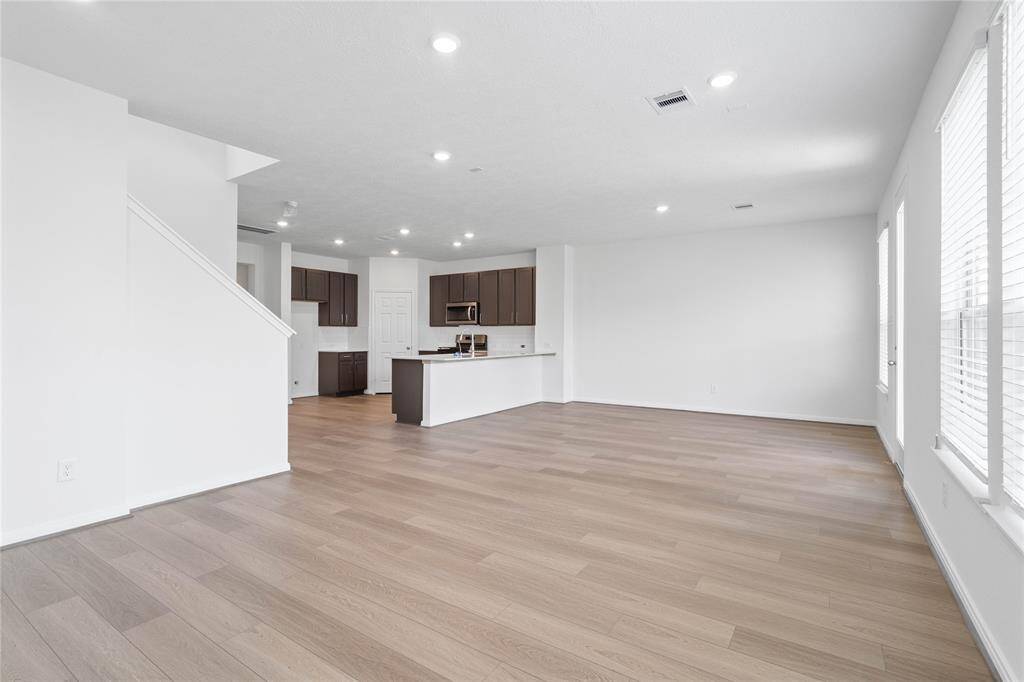 This light and bright spacious family room is the perfect layout for entertaining or just relaxing. Whether it's simply a night in or entertaining family and friends, this home has ample open space for everyone to enjoy! Featuring Bandera vinyl plank flooring in Executive Oak, large windows with blinds, high ceilings, recessed lighting, and wonderful access to your gorgeous kitchen.
