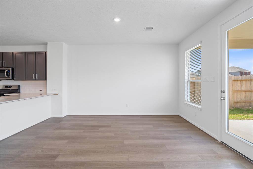 The open concept family, dining and kitchen makes for a great way to keep the party going and never miss a beat! The dining room here features vinyl plank flooring, large window with blinds, warm custom paint, and access door to the back yard.