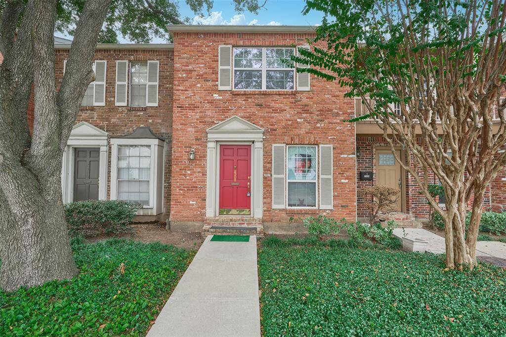 Charming two-story brick townhouse with a striking red door and elegant white-framed windows with shutters. Enjoy a beautifully maintained garden and a welcoming community atmosphere.