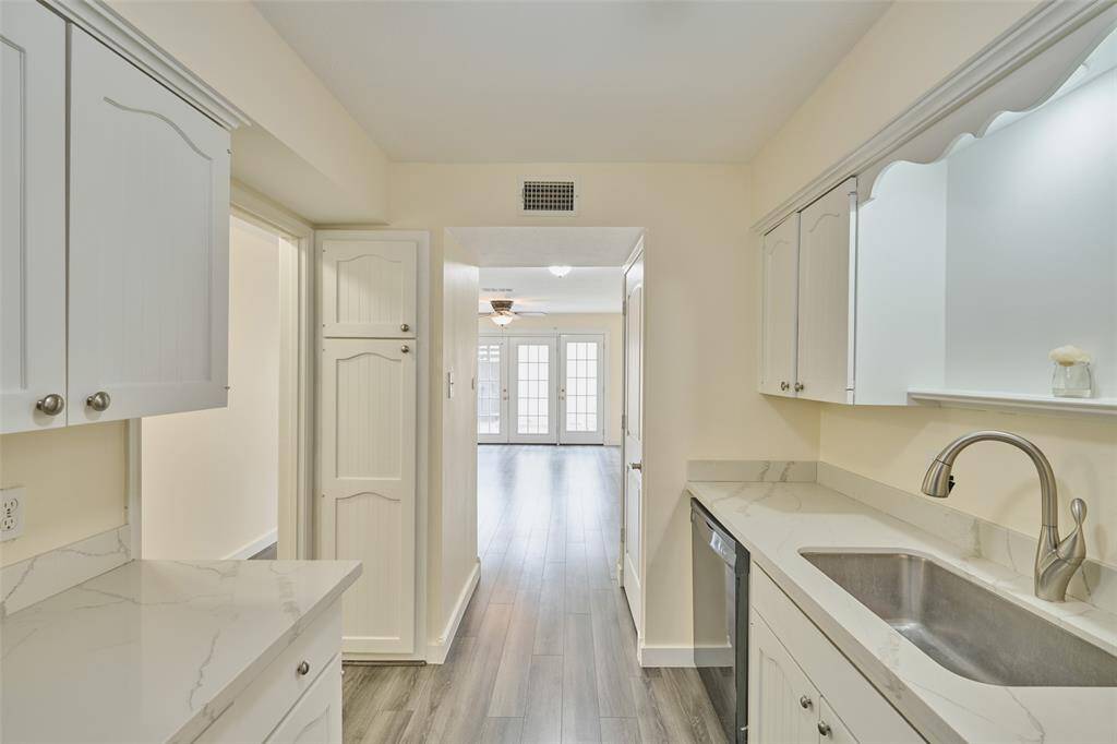Modern kitchen with sleek cabinetry, elegant countertops, and stainless steel appliances, leading to an open, sunlit living area.
