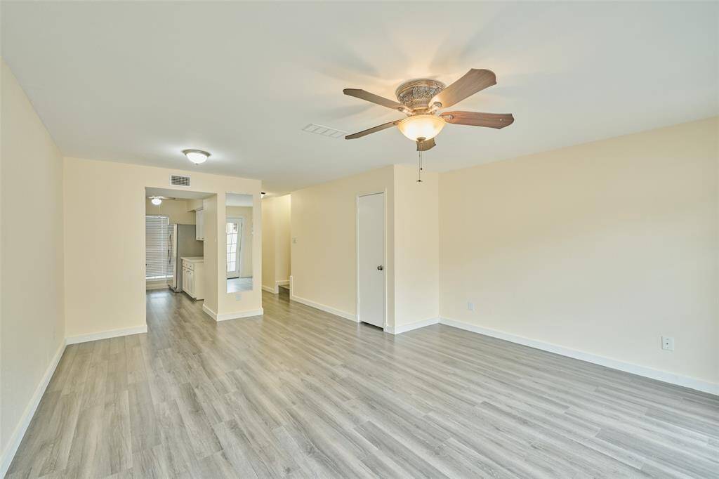 Discover this bright, open-concept room featuring neutral walls, wood-look flooring, a ceiling fan, and abundant natural light.