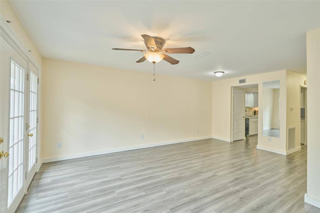 Bright and spacious family room with elegant laminate flooring, ceiling fan, and French doors, seamlessly connecting to the kitchen.