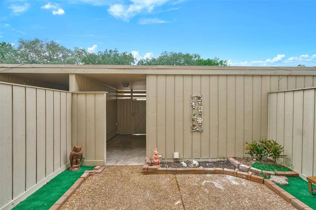 Discover a charming, private outdoor space with a carport, enhanced by a decorative wall piece and ornamental accents. Enjoy the low-maintenance garden and artificial turf for easy upkeep.