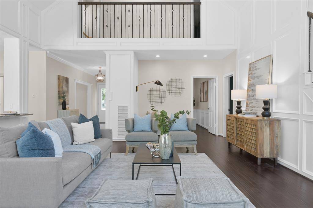 Clean lines and curated elegance define this central living space—framed by airy architectural elements, designer lighting, and a gallery-inspired overlook above.