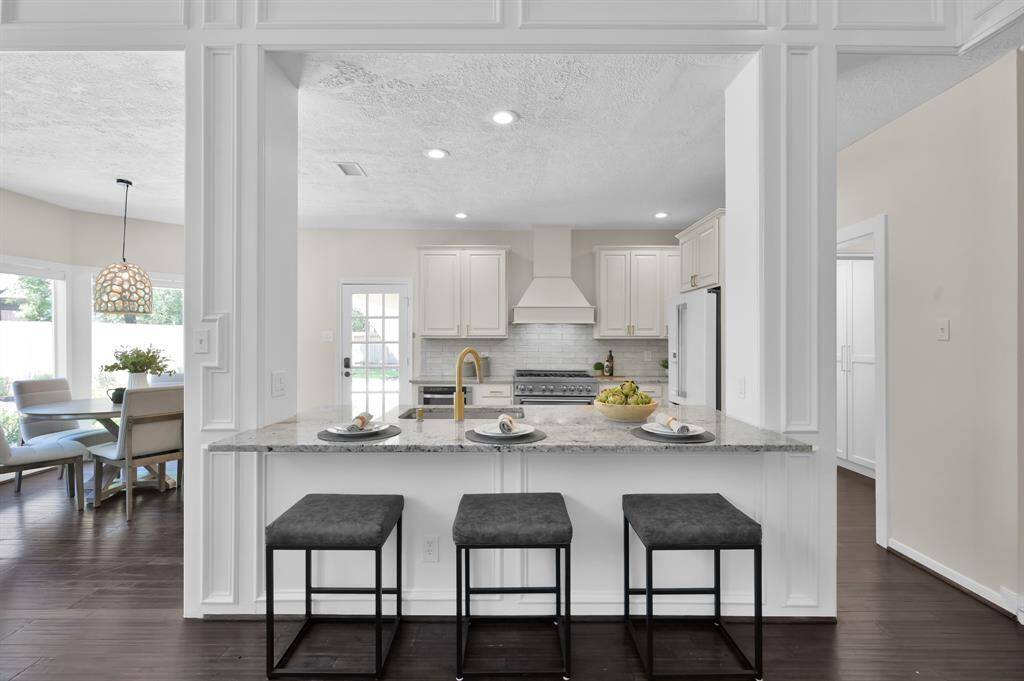Framed by elegant columns, the expansive kitchen island offers casual seating and a stylish connection between the culinary space and living areas—perfect for gathering and conversation.