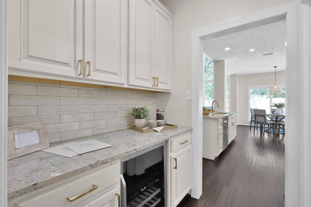 A refined butler’s pantry with custom cabinetry, subway tile backsplash, and a built-in wine fridge—seamlessly connecting kitchen and dining for effortless entertaining