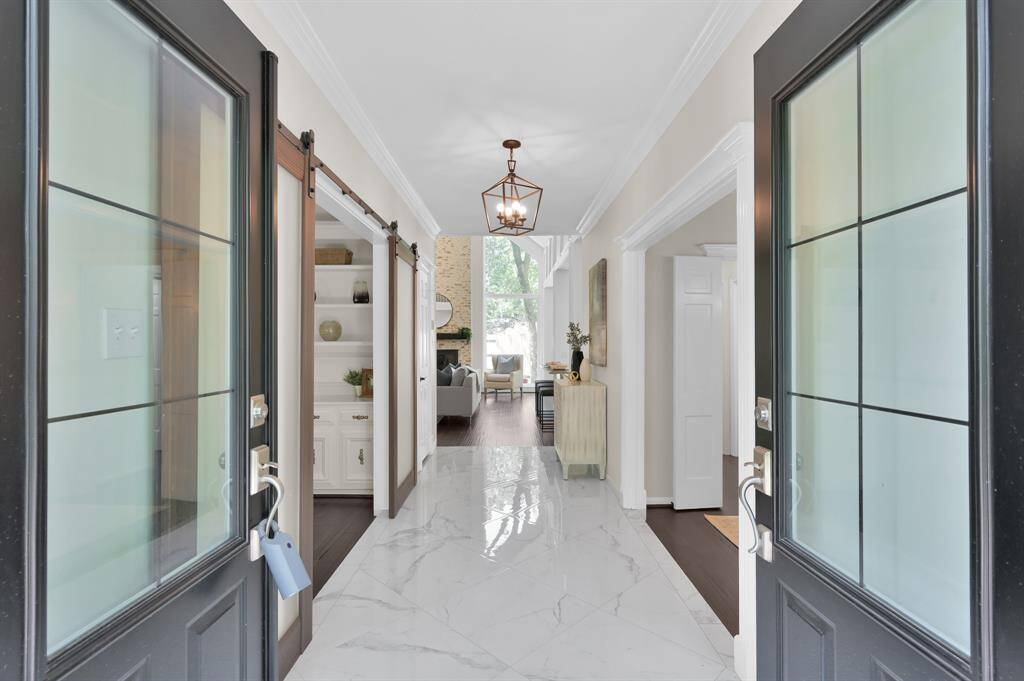 Framed by stately double doors, the grand foyer welcomes with rich hardwood floors, exquisite millwork, and a sightline that speaks to timeless sophistication.
