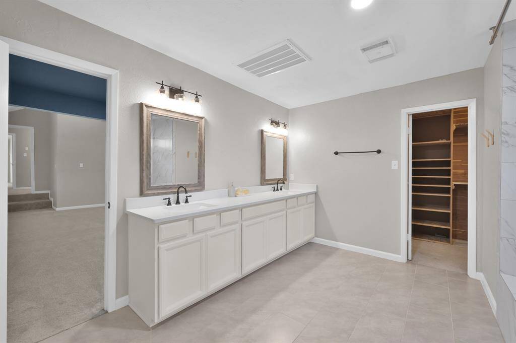 The en-suite bath for the private guest quarters features dual vanities, ample storage, and a spacious walk-in closet—combining comfort, convenience, and privacy in one elegant package.