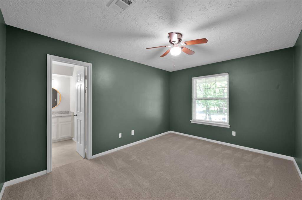 This secondary bedroom offers peaceful green hues, plush carpeting, and an en-suite bath—making it a comfortable and private space for guests or family members alike.