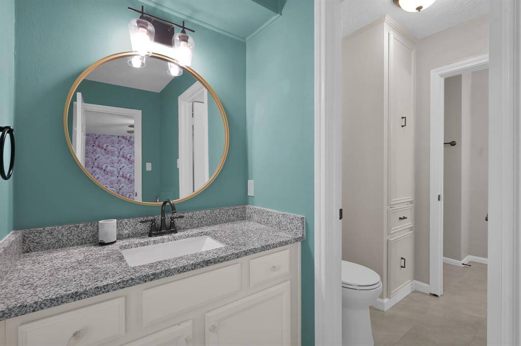 Bright and playful, this secondary bathroom features a vibrant pop of color, granite countertops, and modern finishes—perfectly blending personality with polished design.