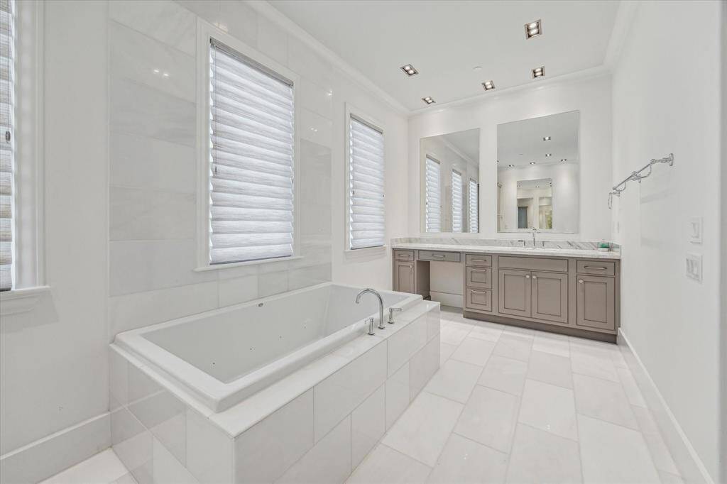 Vanities are found on each side of the primary bath providing plenty of cabinet space and room to get ready for the day.  Multiple windows provide plenty of natural light, while custom shades provide privacy.