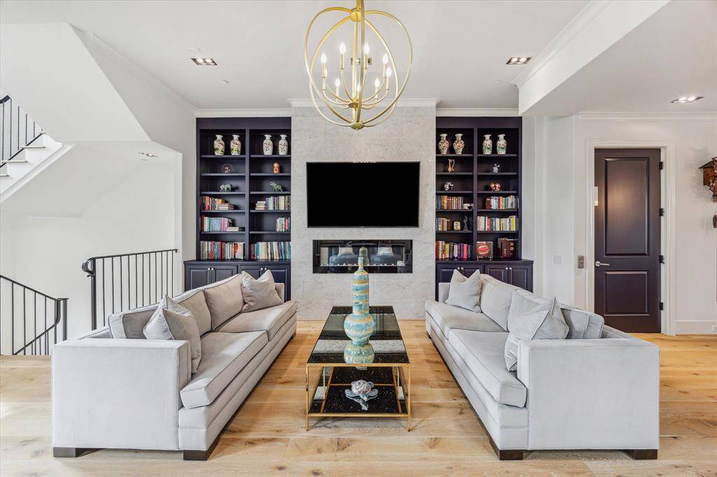 Get cozy with a book in the spacious living room while enjoying the electric fireplace, which is flanked by custom shelving. The stunning brushed brass chandelier provides an air of sophistication.