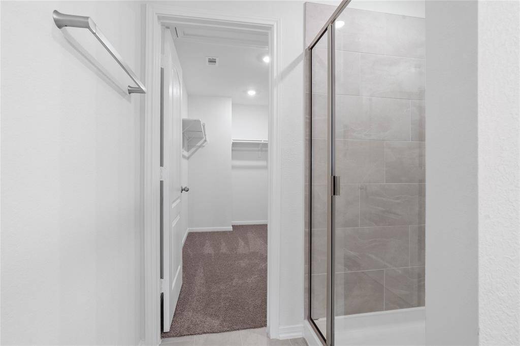 This additional view of the primary bath showcases the walk-in shower with tile surround and walk-in closet.