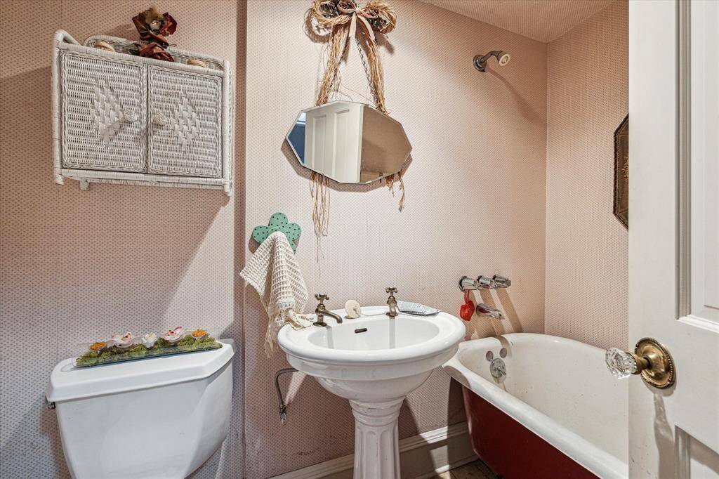 Secondary bathroom with hardwood floors, single sink and soaking tub.