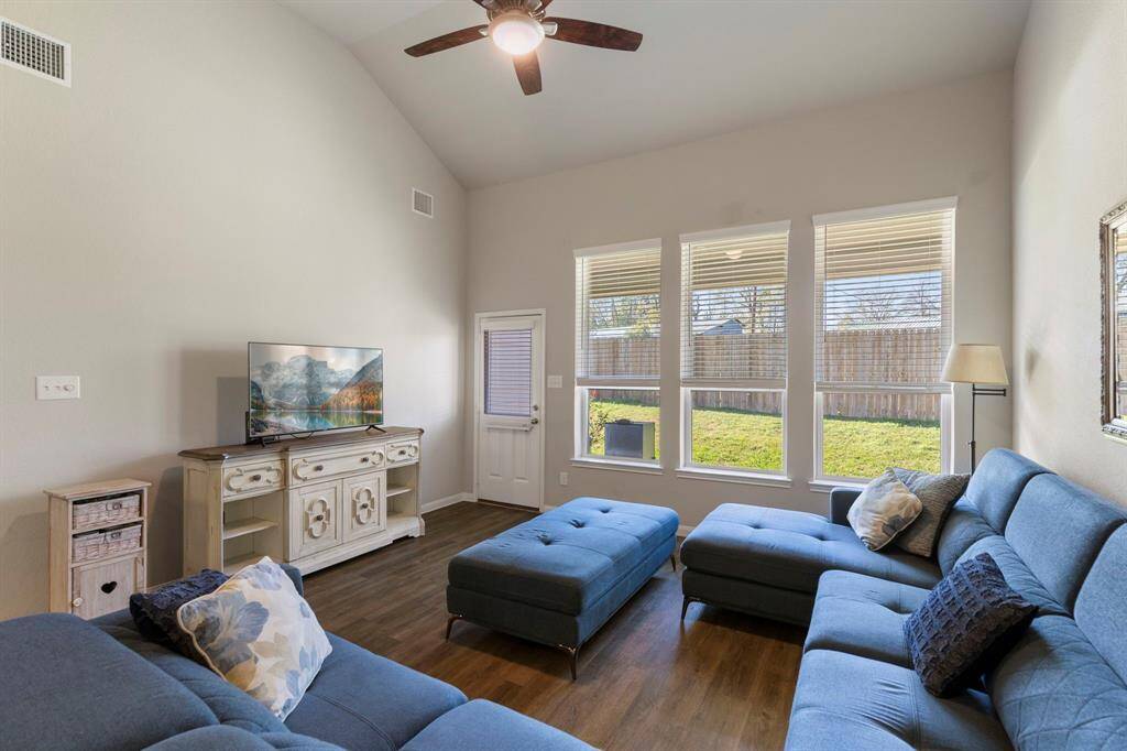 The wall of windows with 2" blinds and vaulted ceiling brings a feel of light and airiness to the room complemented by vinyl plank flooring and updated fan.