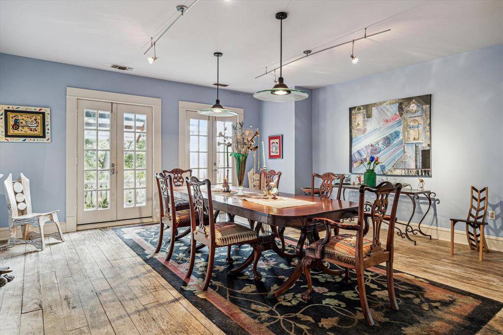 Dining room with hard wood floors, track lighting, and dual french doors to the balcony.