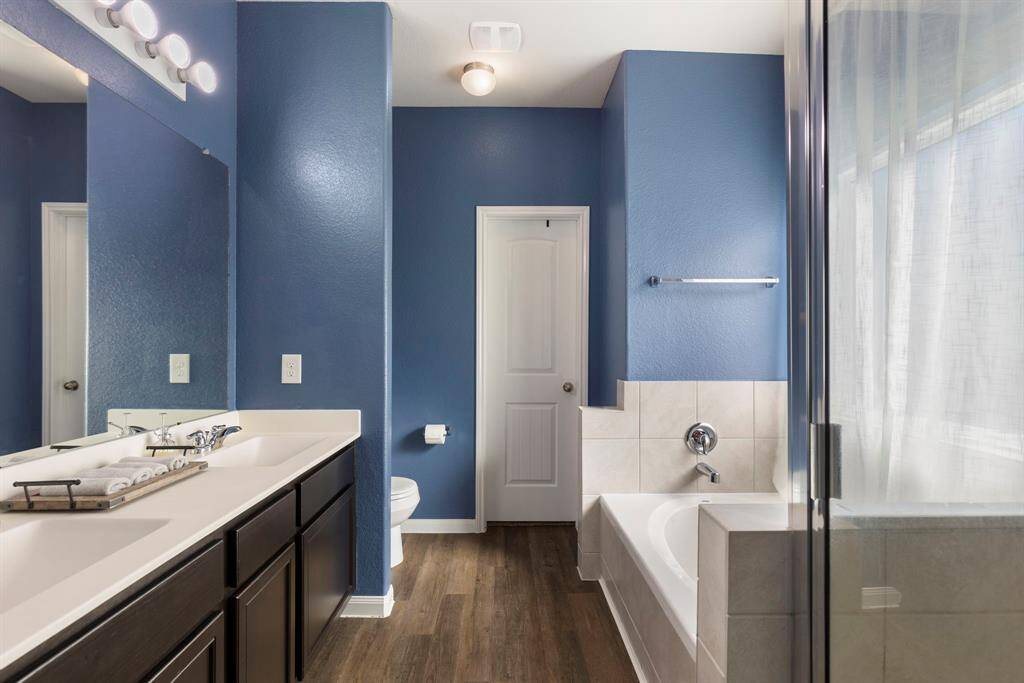 The primary bathroom features a double vanity with marble counter, large mirror and chrome plumbing fixtures. The ensuite bathroom has a large walk-in closet with built in shelving and plenty of hanging space.