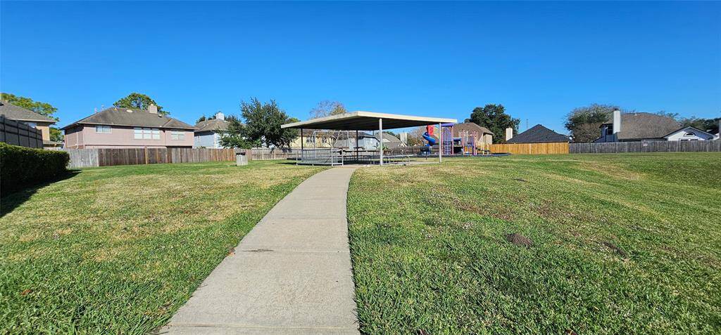 Neighborhood park with a covered picnic area and playground, surrounded by well-maintained lawns and nearby homes