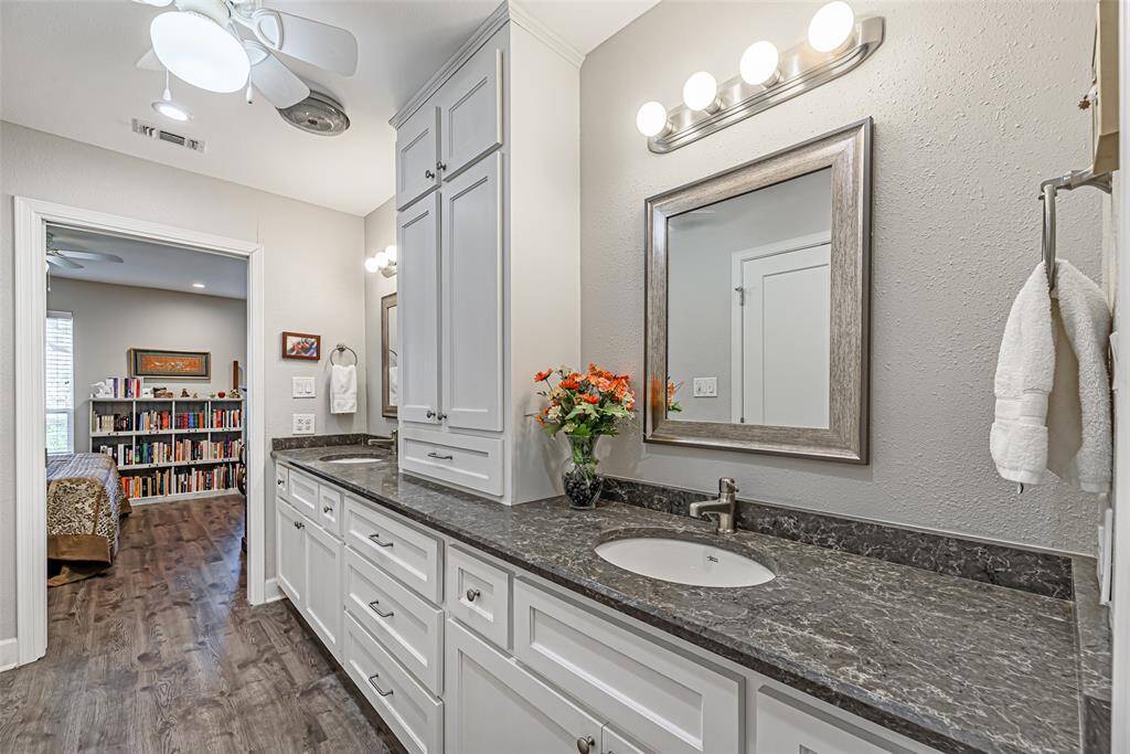 Primary bathroom features lots of storage space, quartz countertops, double sinks and ceiling fan.
