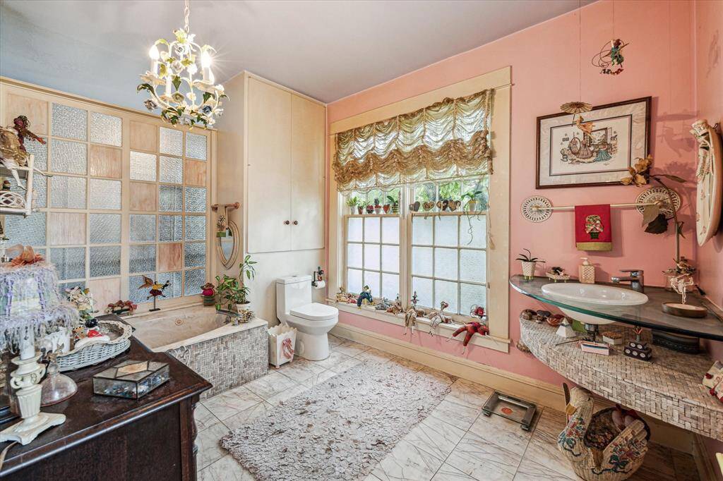 First primary bathroom with tile floors, chandelier, and bathtub.