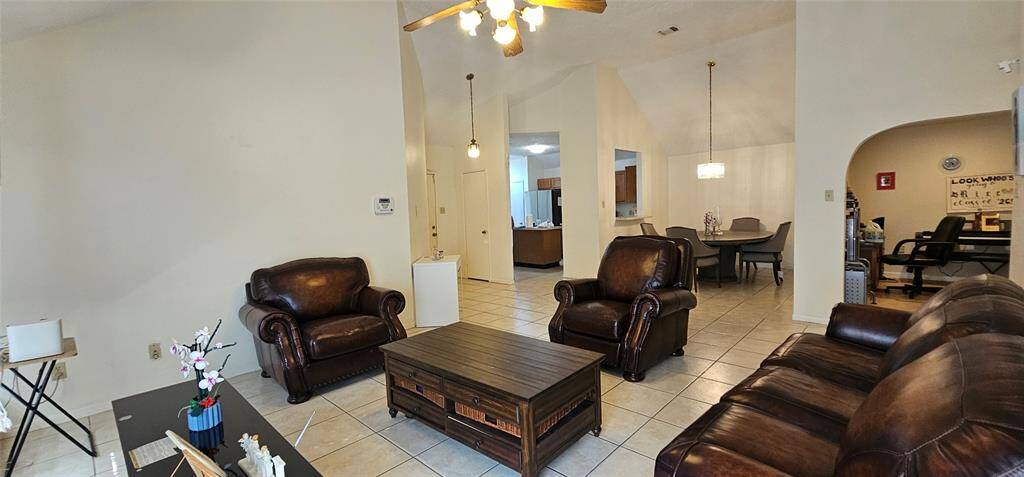 Spacious living room with high ceilings, tiled floors, and ample natural light.