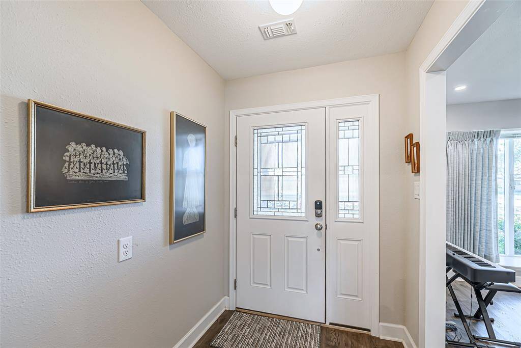 Front entry of the home has white lead glass front door with matching window.