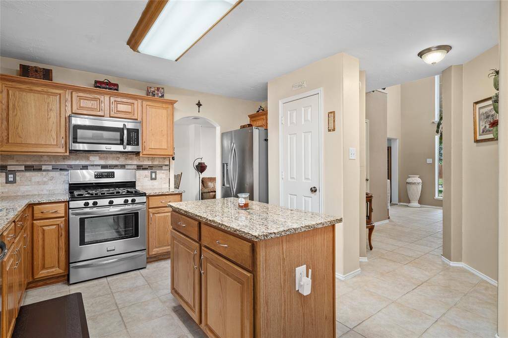 Your contemporary kitchen contains Frigidaire Gallery stainless steel appliances, granite countertops, and honey-toned wooden cabinetry. The kitchen has a tile floor and is open to entry.