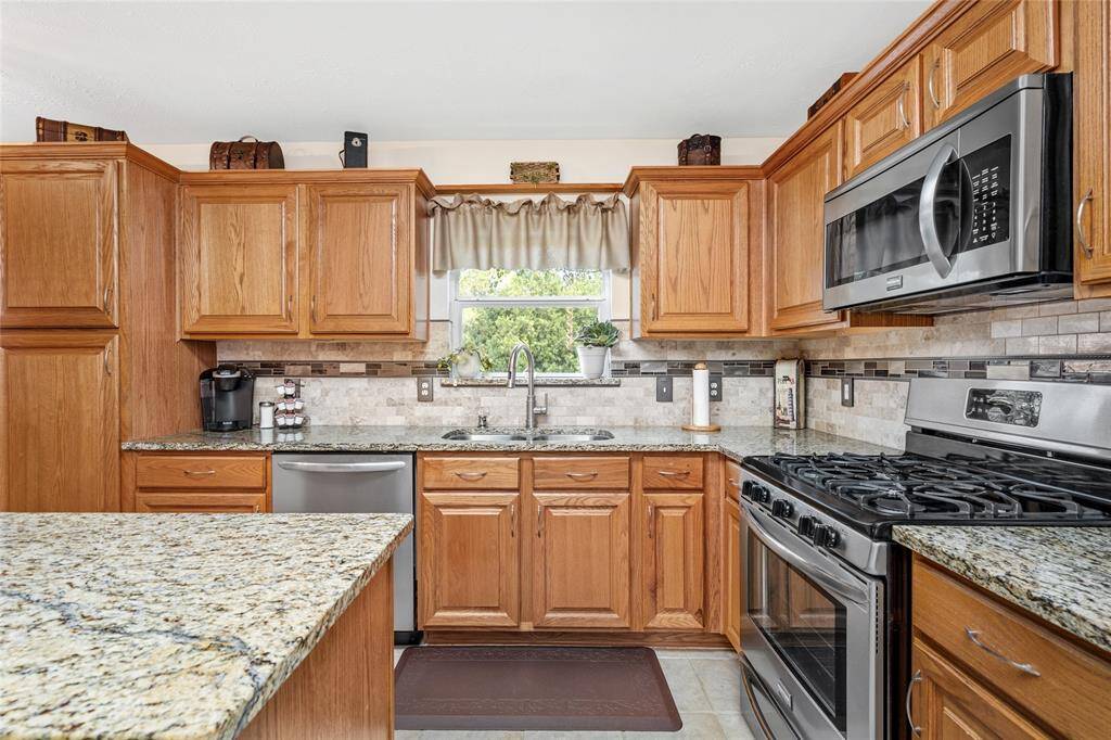 Ample natural wood cabinetry, granite countertops, a tile backsplash, Frigidaire Gallery stainless steel appliance, gas stove and oven are truly your dream kitchen. The window over the sink provide a wonderful view of your back yard.