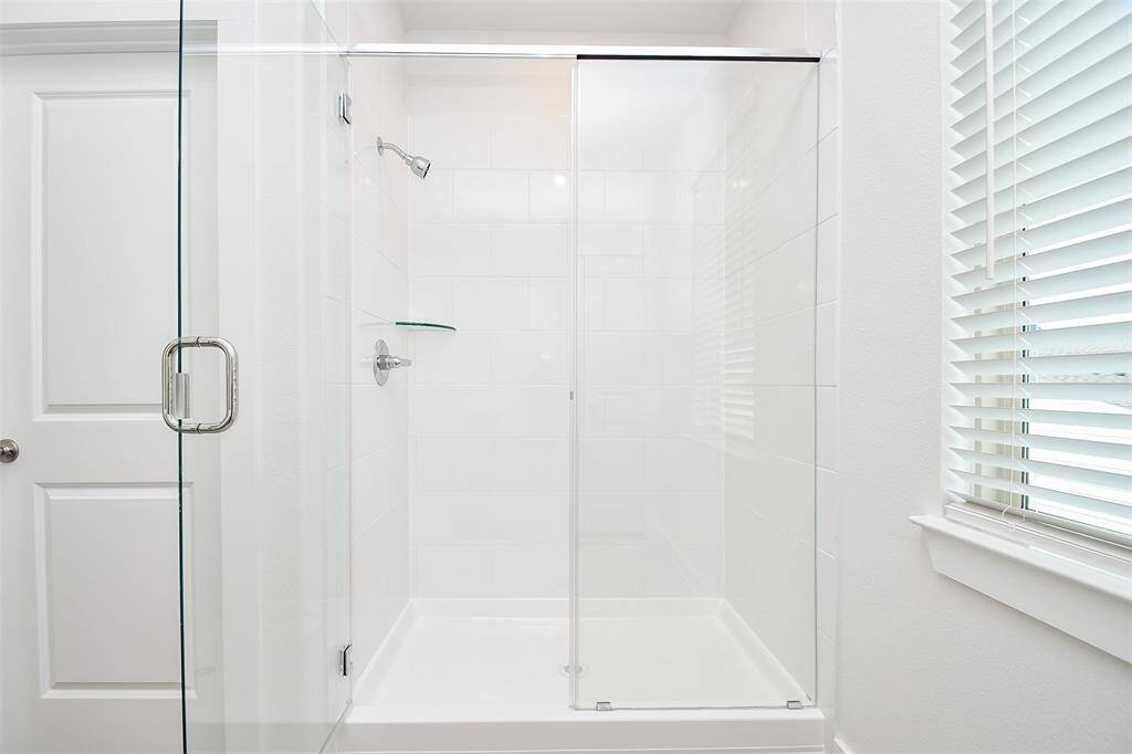 The enclosed shower area features crisp white walls, creating a clean and minimalist aesthetic.