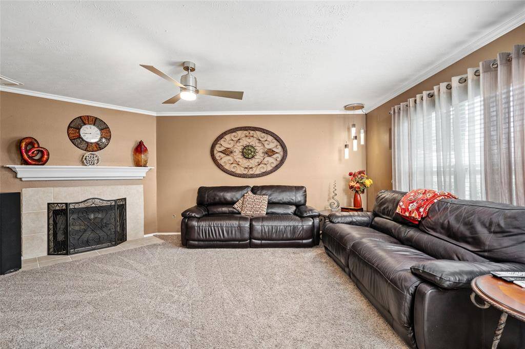 Your living room has a neutral color scheme, fireplace, carpeting, modern ceiling fan, and ample natural light from large windows.