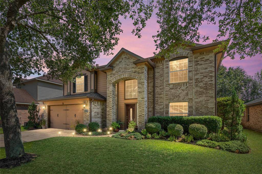 Welcome to your new two-story brick home with a prominent entrance, tall windows, and an attached two-car garage, nestled among mature trees and well-maintained landscaping with underground lawn sprinkler system.
