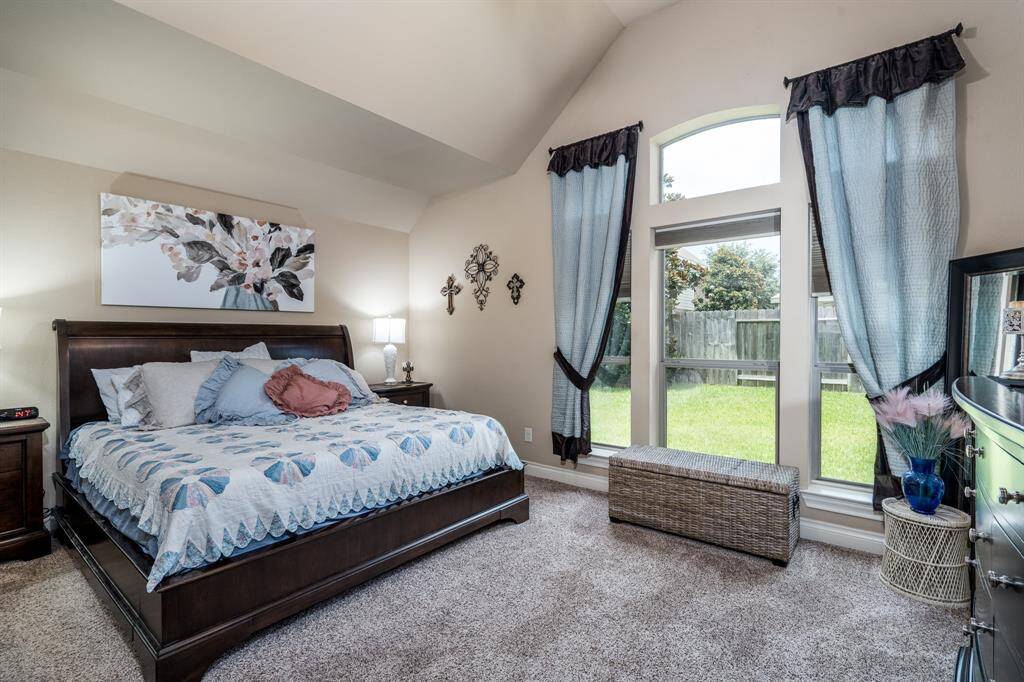 Primary bedroom has high ceiling and large windows and carpet.