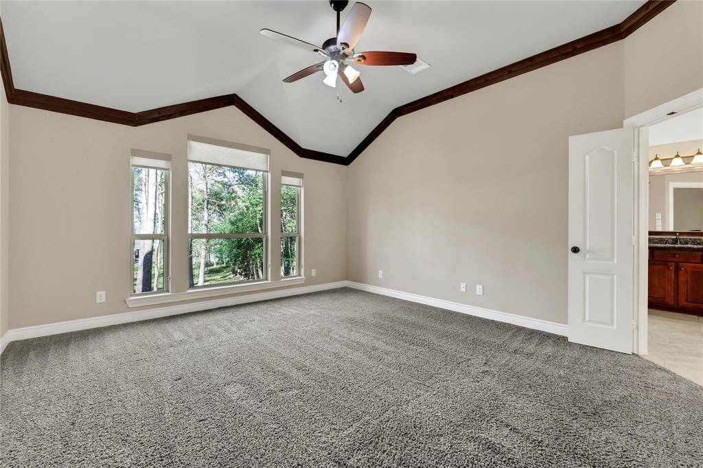 The primary suite has large windows, high ceilings and wood look crown molding - virtually staged