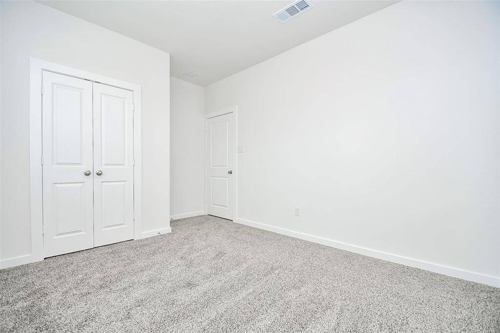 The third bedroom is a cozy space featuring plush carpeting that adds a touch of warmth and comfort.