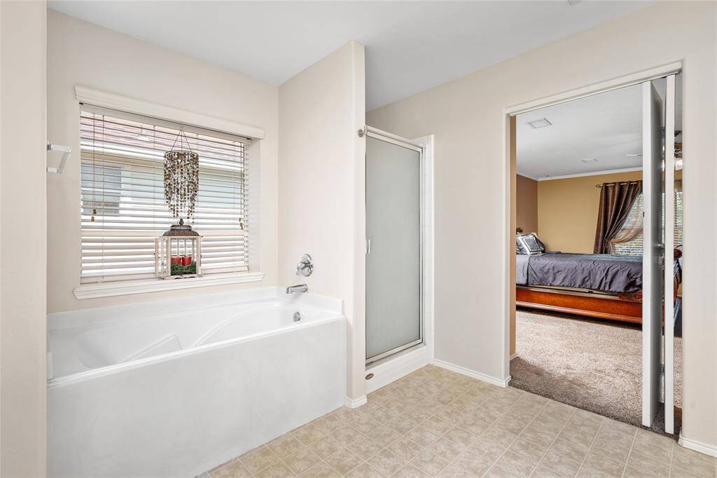 Your ensuite bathroom has a large soaking tub beneath a window, separate shower, and tiled flooring.
