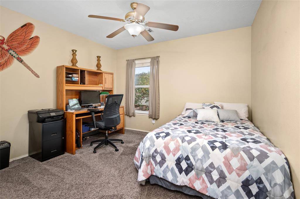 A secondary bedroom has a traditional ceiling fan, ample natural light from a window, and with ample  functional space.