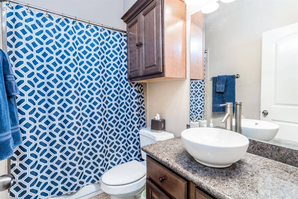 Secondary Bath with combo tub and shower, storage cabinet above the toilet and updated, modern sink.