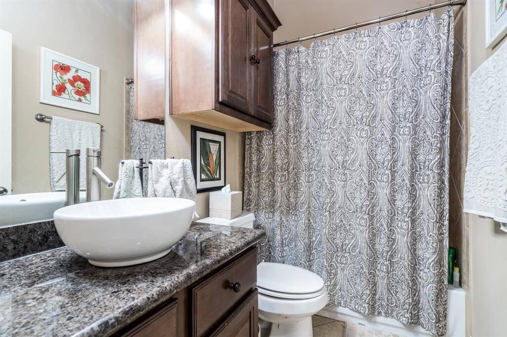 Another secondary bath with storage cabinet over the toilet, modern sink, and combo tub/shower.