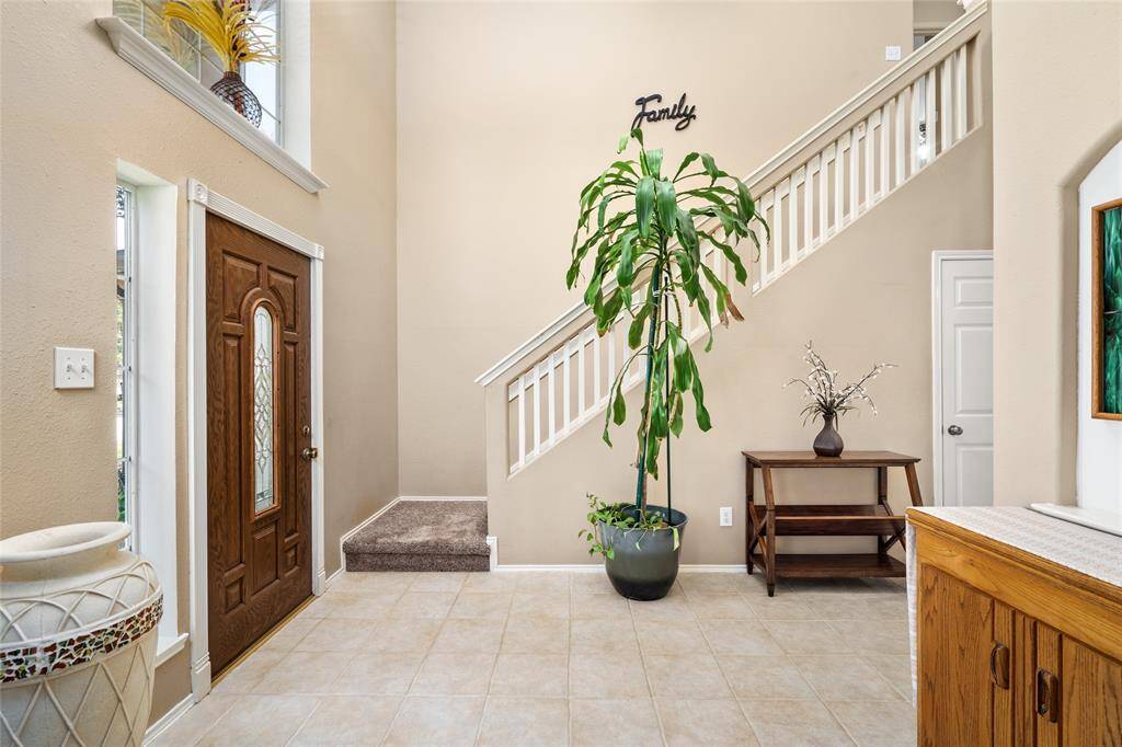 Your spacious and welcoming entryway consists of a high ceiling, tile flooring, a beautiful wooden front door with decorative glass, and a staircase leading to the second level. Add your personal touch to create a warm, homey atmosphere.