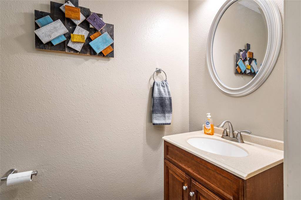 Your convenient downstairs half-bathroom has a wooden vanity with an undermount sink, a large framed mirror,creating a stylish space.