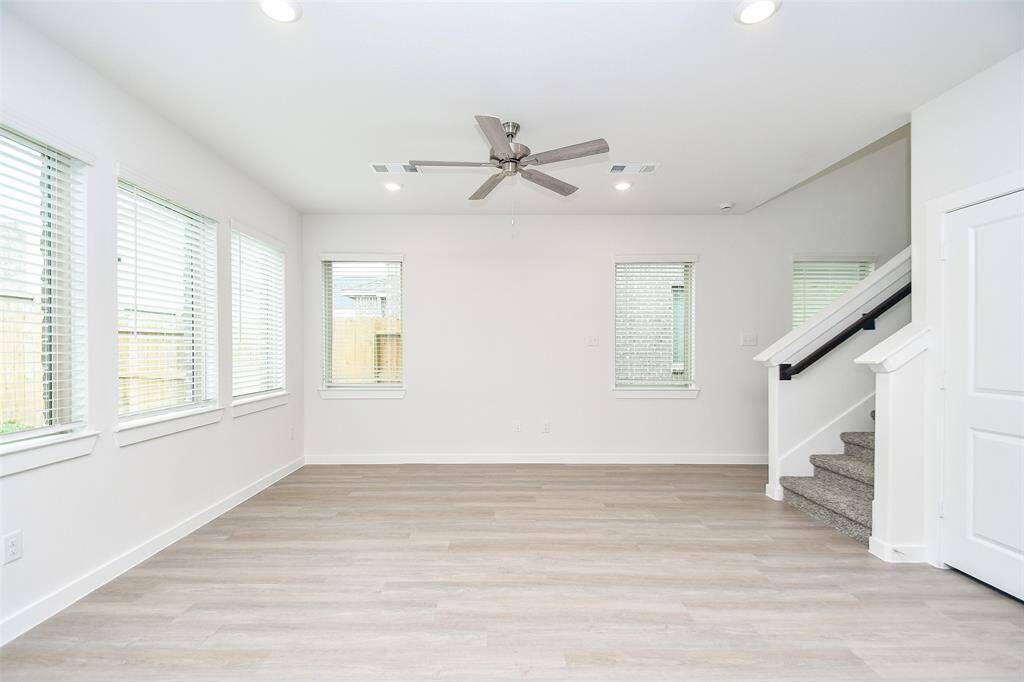 Relax and unwind in this spacious living room, featuring a ceiling fan for added comfort and large windows that offer plenty of natural light and a bright, airy atmosphere.