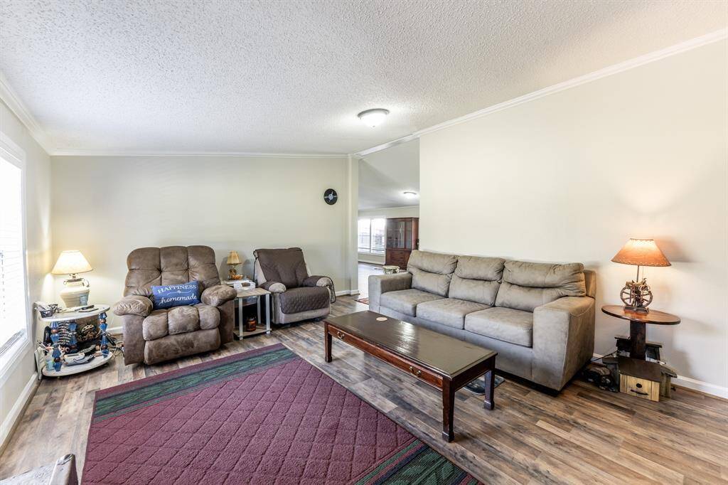 This cozy living room features comfortable seating, soft lighting, and wood-look flooring, creating a warm and inviting atmosphere.