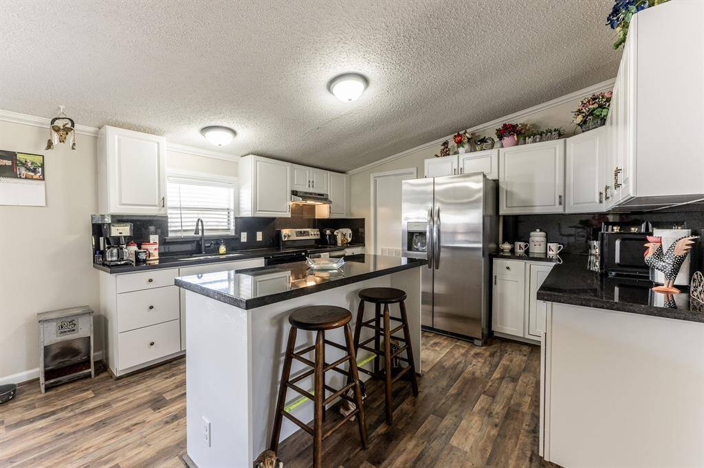 Sleek kitchen with a central island, ample counter space, and brand-new appliances, countertops, and flooring. Perfectly positioned near the living area for convenience yet maintains privacy.