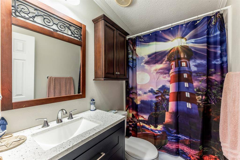 Charming second bathroom featuring a stylish vanity, elegant fixtures, and a vibrant lighthouse-themed shower curtain.