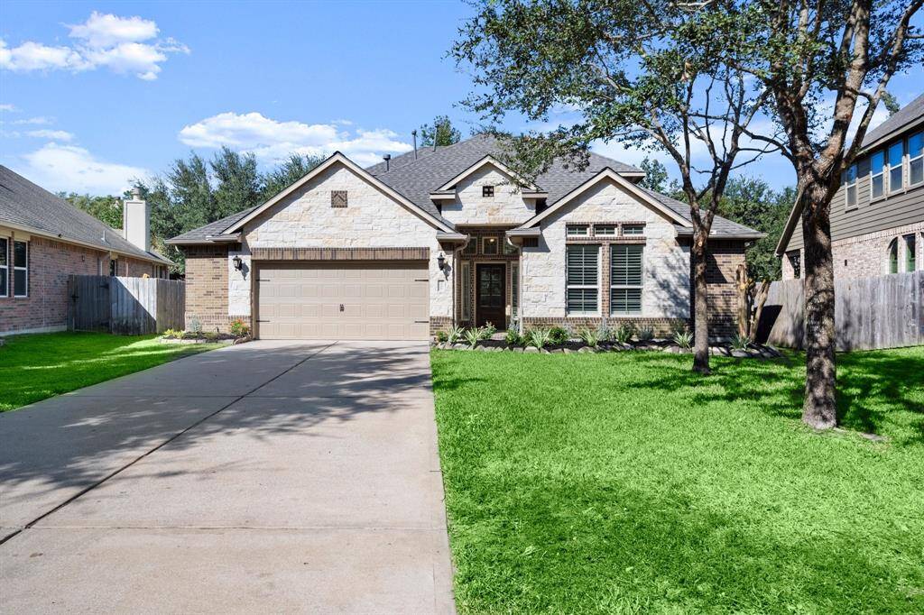 This charming home showcases fantastic curb appeal with its modern stone and brick exterior, a manicured front lawn, and a long driveway leading to a spacious two-car garage.