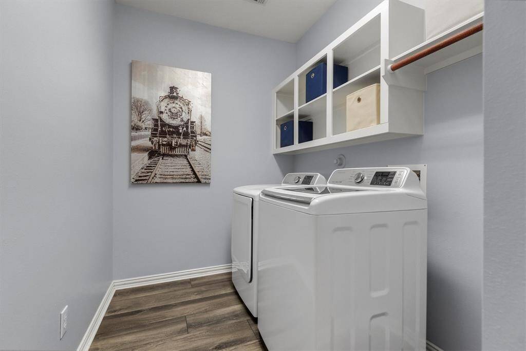 This is a tidy laundry room featuring ample shelving, a neutral color palette and modern flooring.